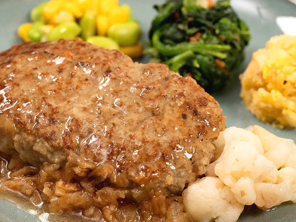 ナッシュのオニオングリルハンバーグ｜玉ねぎの旨みソースとふっくらジューシーなハンバーグ、副菜（枝豆コーンサラダ・ほうれん草ソテー・卵入りポテトサラダ・カリフラワー）付き