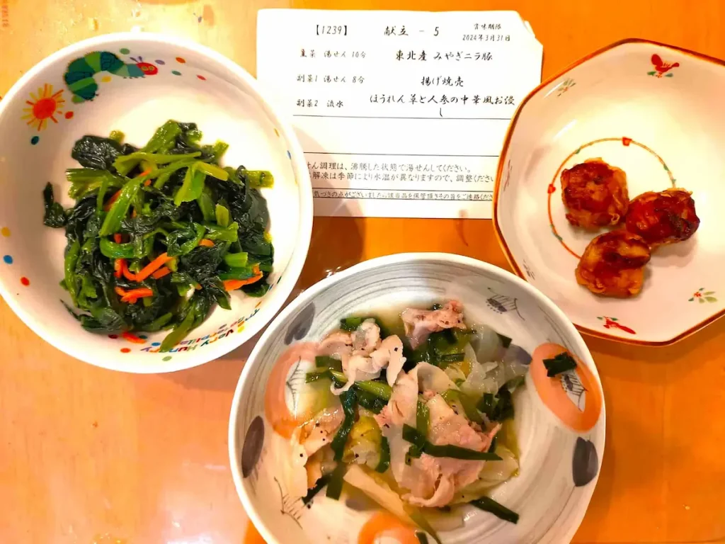 わんまいるの健幸ディナー例。揚げ焼売、ほうれん草と人参の中華風お浸し、豚肉と野菜の煮物が並んだ彩り豊かな和食セット。