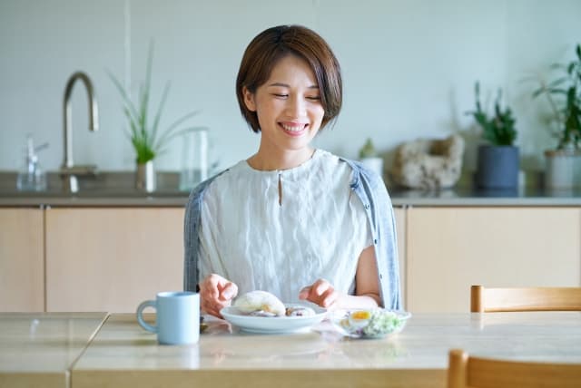 ナッシュの宅配弁当を笑顔で食べる女性のイメージ。月額料金や送料をシミュレーションした記事のサムネイル