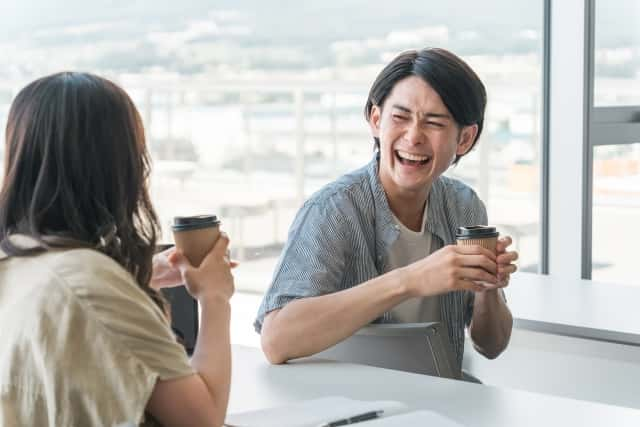 友人とコーヒーを楽しむ笑顔の男性の画像