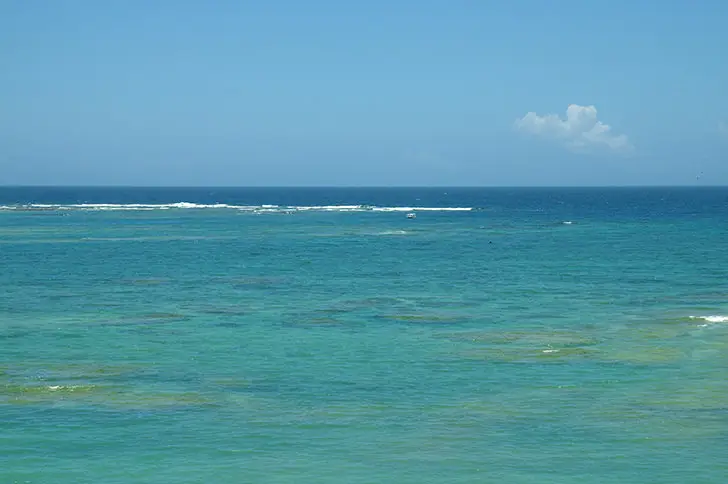 沖縄の美しい海と青い空を写した写真、透明度の高い海水と砂浜が特徴