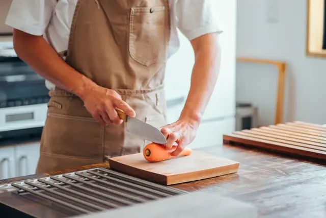 自宅のキッチンで野菜を切りながら料理を楽しむ人の様子。自炊や料理そのものが好きな人はナッシュが向かない場合がある